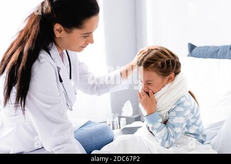 Arzt berührt Kopf von quetschen Mädchen im Bett sitzen Stockfoto