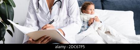 Arzt schreibt Rezept in der Nähe krank, verärgert Kind im Bett liegen, Banner Stockfoto