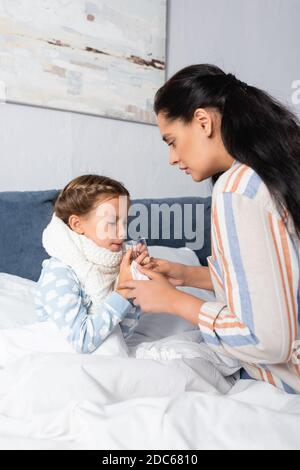 Frau, die der kranken Tochter ein Glas Wasser gab Bett Stockfoto