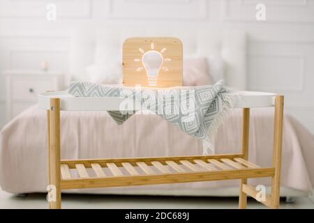 Holz Lapms und Dekor Details zu Hause Interieur. Stilvolle Holz handgemachte Lampe mit elektrischer Glühbirne ausgeschnittenes Bild, auf kleinen Couchtisch Stockfoto
