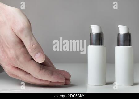 Nahaufnahme eines Paares ausgestreckter schmutziger Hände vor 2 Flaschen hydroalkoholisches Desinfektionsgel. Stockfoto