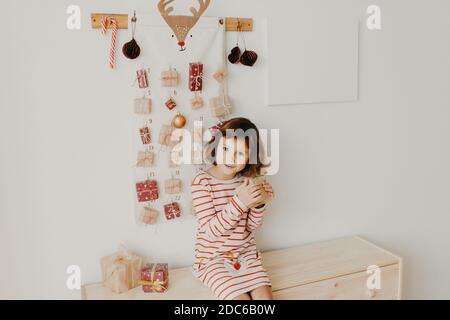 Nettes Mädchen Eröffnung Weihnachten Adventskalender Geschenke. Verpackte Geschenke für Kinder. Saisonale Tradition. Umweltfreundliche Weihnachten Stockfoto