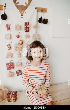 Nettes Mädchen Eröffnung Weihnachten Adventskalender Geschenke. Verpackte Geschenke für Kinder. Saisonale Tradition. Umweltfreundliche Weihnachten Stockfoto