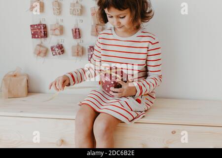 Nettes Mädchen Eröffnung Weihnachten Adventskalender Geschenke. Verpackte Geschenke für Kinder. Saisonale Tradition. Umweltfreundliche Weihnachten Stockfoto