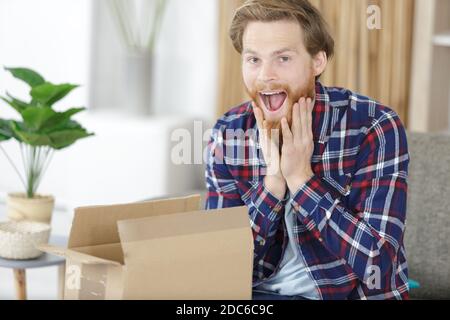 Überrascht Mann öffnen Karton-Box Stockfoto