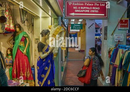 Eine ethnische Inderin in Buffalo Road, Little India, Singapur, die an Schaufenstern mit einer Ausstellung traditioneller indischer Frauenkleider vorbeikommt Stockfoto