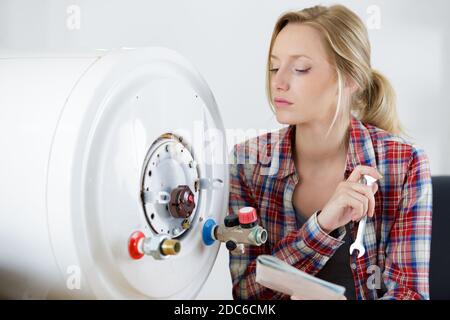 Weibliche auszubildende Klempner Arbeiten an zentralen Heizkessel Stockfoto