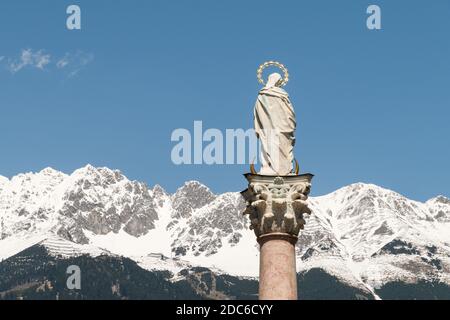 Nahaufnahme von der Jungfrau Maria auf der Annassäule in Innsbruck, Österreich. Die schneebedeckten Berge der Alpen sind im Hintergrund. Stockfoto