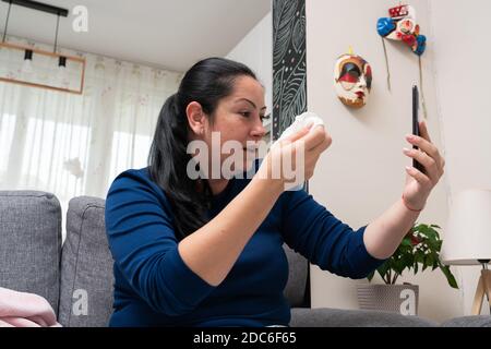 Erwachsene Frau, die sich krank fühlt, macht Videoanruf mit dem mobilen Smartphone Sitzen auf der Couch zu Hause als covid19 Symptome Konzept Stockfoto