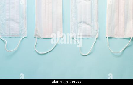 Layout von vier weißen und blauen medizinischen Masken auf einem Blauer Hintergrund, Draufsicht Stockfoto