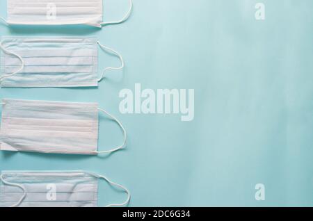 Layout von vier weißen und blauen medizinischen Masken auf einem Blauer Hintergrund, Draufsicht Stockfoto