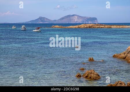 Tavolara, Sardinien / Italien - 2019/07/18: Tyrrhenisches Meer mit Yachten vor der Küste Isola Tavolara mit Capo Figari Kap, Monte Ruju Gipfel und Golfo Ar Stockfoto