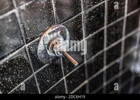 Nahaufnahme der modernen schwarzen Dusche Badewanne mit blauen Vorhängen im Badezimmer in Modell Haus, Wohnung oder Haus, Fliesen, Wasserhahn, Tropfen Wasser Stockfoto