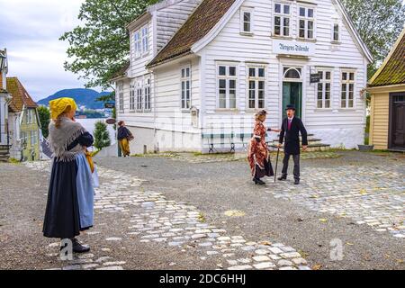 Bergen, Hordaland / Norwegen - 2019/09/06: Rekonstruierte norwegische Stadtstraße aus dem 19. Jahrhundert mit Holzhäusern und inszenierten sozialen Szenen in Old Bergen Mus Stockfoto