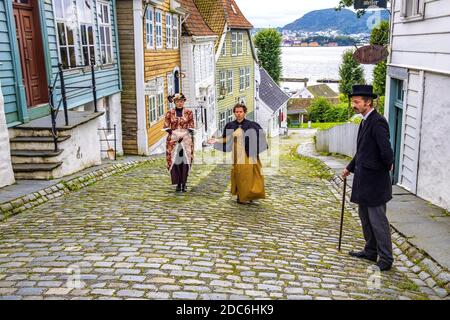 Bergen, Hordaland / Norwegen - 2019/09/06: Rekonstruierte norwegische Stadtstraße aus dem 19. Jahrhundert mit Holzhäusern und inszenierten sozialen Szenen in Old Bergen Mus Stockfoto