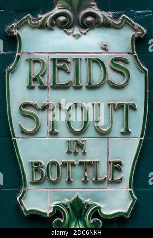 Eine Nahaufnahme EINER Vintage Keramik gekachelt Werbung für Reid's Stout in A Bottle auf der Außenseite EINES Pubs in London, Großbritannien Stockfoto