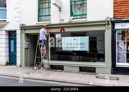 Ein Wegweiser Painting A Sign on A Shop, High Street, Lewes, East Sussex, Großbritannien Stockfoto
