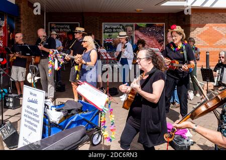 Eine Ukulele Band spielt Musik außerhalb des Tesco Supermarket zur Unterstützung der lokalen Foodbank, Lewes, East Sussex, UK. Stockfoto