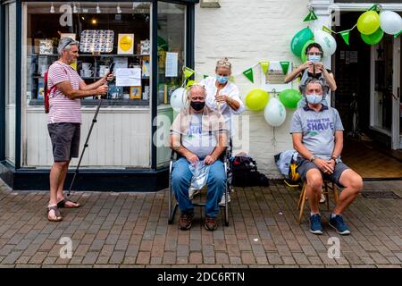 Männer, die ihre Haare abschütteln, um Geld für die Macmillan Cancer Care Charity, High Street, Lewes, East Sussex, Großbritannien zu sammeln. Stockfoto