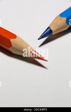 Extreme Nahaufnahme von scharfen blauen und roten Bleistiften auf weißem Hintergrund. Stockfoto