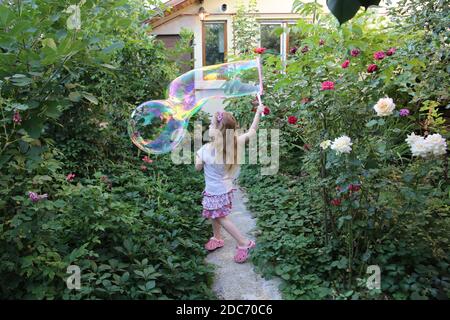 Blonde kleine Mädchen spielt mit riesigen Seifenballons Stockfoto