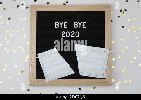 Schwarzes Briefbrett mit Text BYE BYE 2020 mit Cut-Maske auf weißem Hintergrund mit kleinen Sternen. Draufsicht. Neujahr Weihnachten minimalen Hintergrund Stockfoto