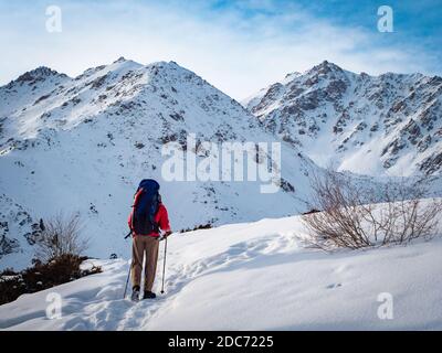 Ein Mann mit Rucksack reist im Winter in die Berge. Schöner sonniger Wintertag Stockfoto