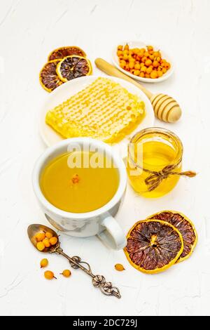Heilender Sanddorntee köstlich aromatisch voller Vitamin- und Mikroelemente. Honig, frische Beeren, Honigwaben und Zitrone. Weißer Kitt Hintergrund, Klo Stockfoto