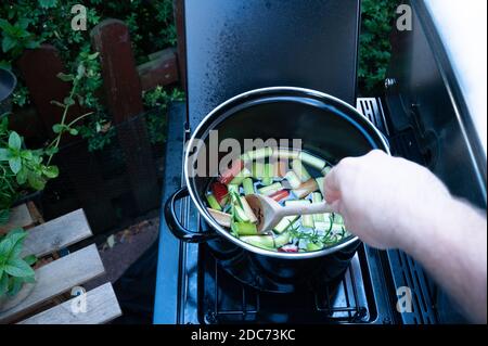 Rhabarber kocht in einem Topf, ein Mann rührt sich sanft Stockfoto