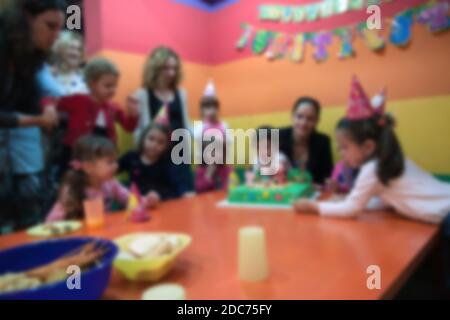 Verschwommene Kinder mit ihren Müttern bei der Geburtstagsfeier im Spielzimmer. Bild für die Verwendung im Hintergrund. Stockfoto