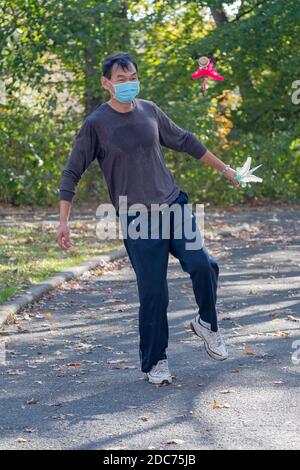 Ein flinker Chinese American Mann startet einen Kick in einem Jianzi Spiel in einem Park in Flushing, Queens, New York City. Stockfoto