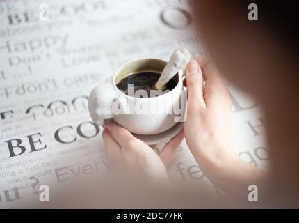 Nahaufnahme der Hände einer Frau, die eine Tasse Kaffee hält Stockfoto