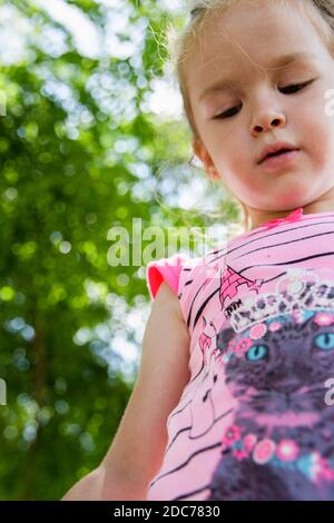 Kleine blonde Mädchen spielt im Park mit Seifenblasen Stockfoto