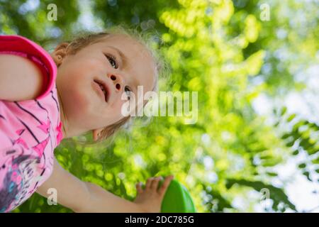 Kleine blonde Mädchen spielt im Park mit Seifenblasen Stockfoto