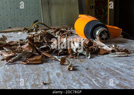 Restaurierung einer alten Tür. Alte Lackschichten mit einer Heißluftpistole und einem Spachtel entfernen. Nahaufnahme . Verdrehte Stücke von alter brauner Farbe. Stockfoto