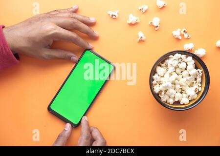 Mann Hand mit Smartphone und essen Popcorn Stockfoto