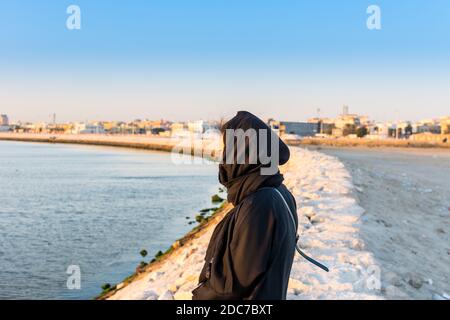 Eine muslimische Frau trägt schwarzen Hijab beobachten Sonne aus dem Meer am corniche Park in Dammam, Königreich Saudi-Arabien Stockfoto