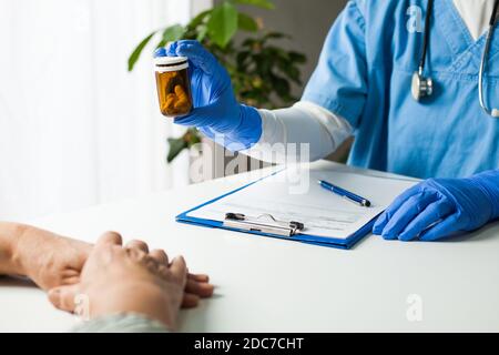 Hausarzt UK GP Arzt hält Flasche verschreibungspflichtige Medikamente, Übergabe Über zum Patienten während der medizinischen Untersuchung, Healthcare Professional-Pensum Stockfoto