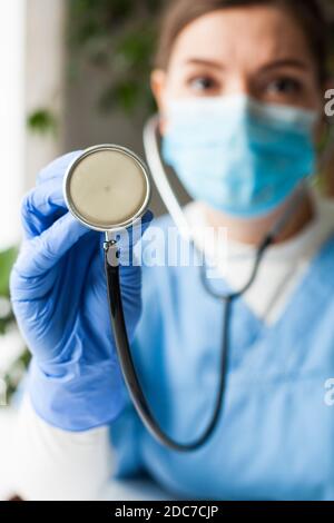 Kaukasische Ärztin, die ein Stethoskop hält, auf den Körper des Patienten hört, um Geräusche von Herz, Lunge, Darm, Messung des Blutdrucks, Diagno Stockfoto