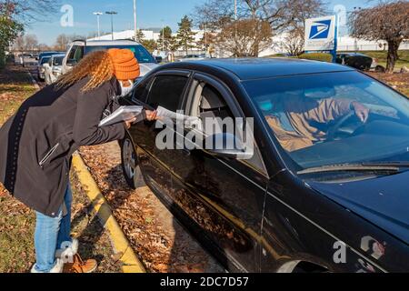 Allen Park, Michigan, USA. November 2020. Während der Coronavirus-Pandemie veranstaltete die US-Post Drive-Thru-Jobmessen in Detroit und den Vorstadtgemeinden. USPS ist die Einstellung für feste und saisonale Positionen. Jewel Mays übergab Bewerbern außerhalb des Allen Park Network Distribution Center Einstellungsinformationen. Kredit: Jim West/Alamy Live Nachrichten Stockfoto