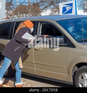 Allen Park, Michigan, USA. November 2020. Während der Coronavirus-Pandemie veranstaltete die US-Post Drive-Thru-Jobmessen in Detroit und den Vorstadtgemeinden. USPS ist die Einstellung für feste und saisonale Positionen. Jewel Mays übergab Bewerbern außerhalb des Allen Park Network Distribution Center Einstellungsinformationen. Kredit: Jim West/Alamy Live Nachrichten Stockfoto