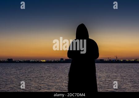 Eine muslimische Frau trägt schwarzen Hijab beobachten Sonne aus dem Meer am corniche Park in Dammam, Königreich Saudi-Arabien Stockfoto