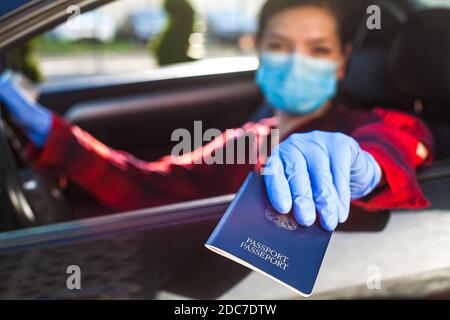 Junge Frau mit blauem Pass durch das Autofenster, Patrouille Grenzschutz Personal Kontrollkontrolle, Coronavirus Immunität Karte Gesundheit Pass, Sicherheit Stockfoto