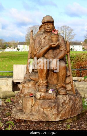 Die Skulptur zeigt zwei Figuren, die als Soldat im Ersten Weltkrieg und später als Kindergärtner dargestellt sind. Die Skulptur ist aus einer Eiche gefertigt. Stockfoto