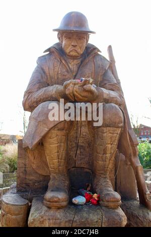 Die Skulptur zeigt zwei Figuren, die als Soldat im Ersten Weltkrieg und später als Kindergärtner dargestellt sind. Die Skulptur ist aus einer Eiche gefertigt. Stockfoto