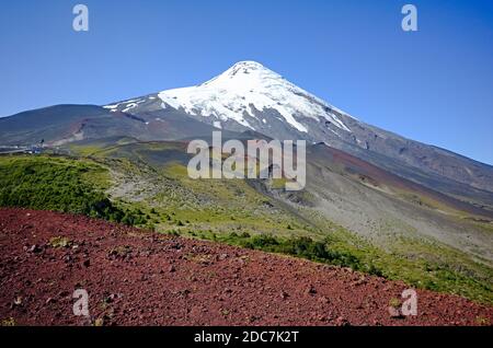 Osorno Vulkan Blick aus dem Krater auf Hängen mit schönen Farben der roten, grünen und schneebedeckten Vulkan Gipfel und klaren blauen Himmel. Stockfoto