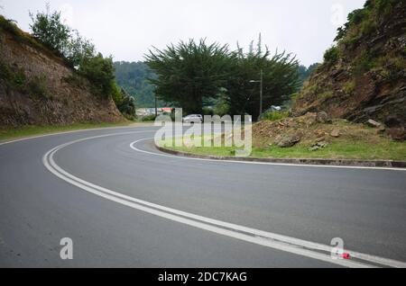 Leere kurvige Straße in einem kleinen Dorf an der Pazifikküste Chiles. Bahia Mansa, Chile. Stockfoto