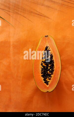 Kreativer Hintergrund mit Papaya und Blatt auf dem Hintergrund. Hintergrund für das Essen. Vertikale Ausrichtung mit Platz für Text. Stockfoto