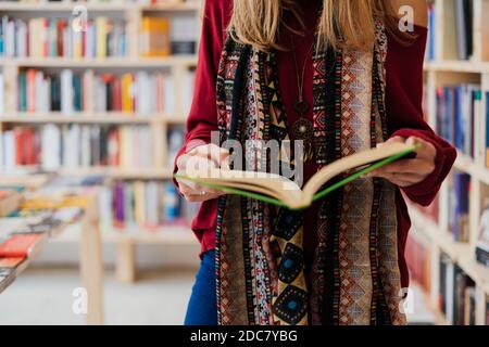 Die Hände einer jungen Frau, die ein Buch in einer Buchhandlung hält Stockfoto