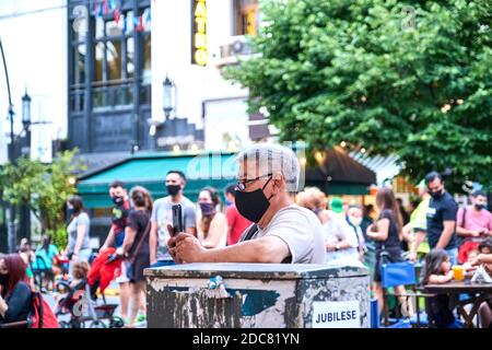 Buenos aires / Argentinien; 14. Nov 2020: Mann mit Schutzmaske, der während der Coronavirus-Pandemie eine Straßenmusikshow mit seinem Telefon aufnahm, C Stockfoto